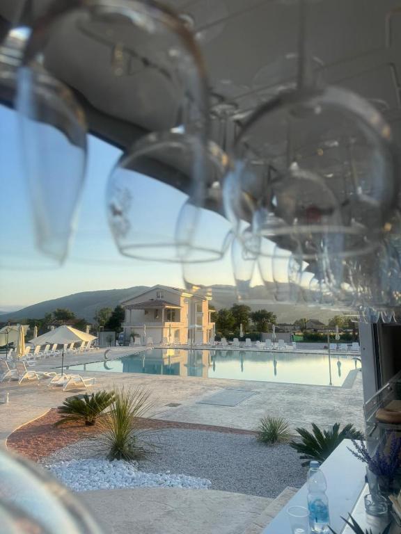 a view of a pool with wine glasses in the foreground at Tenuta il Bandito in Montesano Scalo