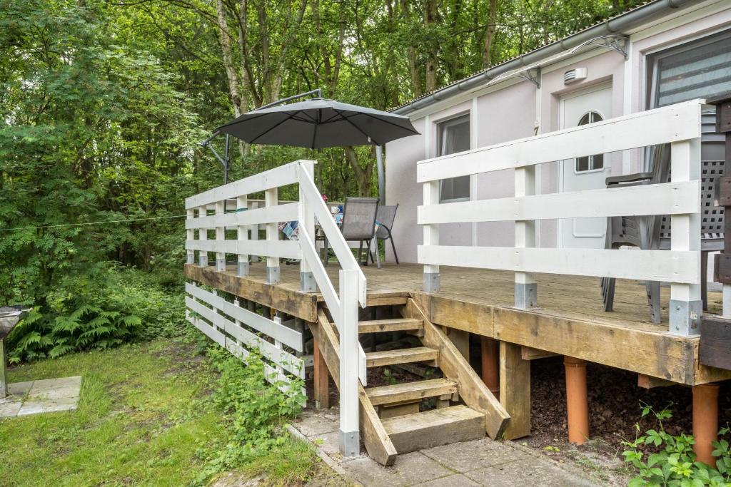 a wooden deck with an umbrella and a staircase at Bungalow Seeschwalbe, Nr 7 in Dranske