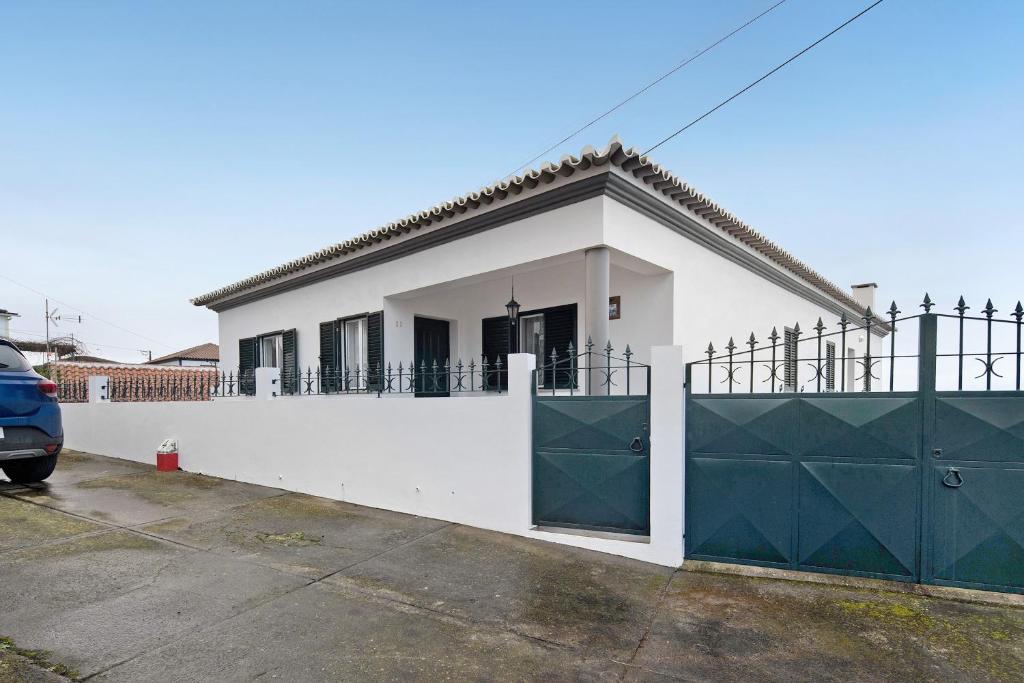 a white house with a fence and a gate at Casa das Hortênsias in Raminho