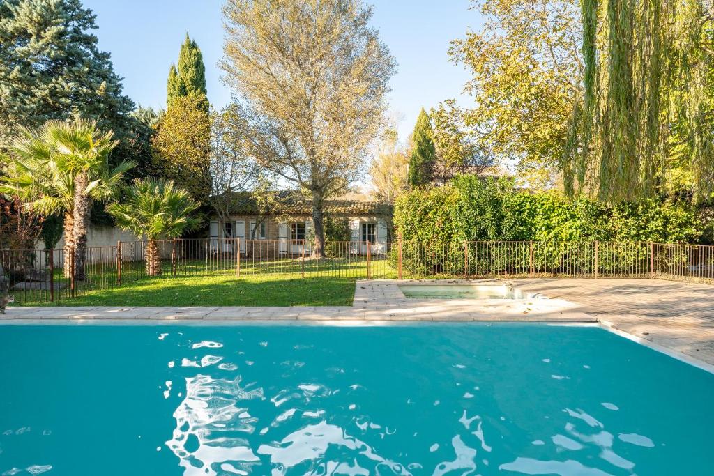 a swimming pool in front of a house with trees at Le Patio in Velleron