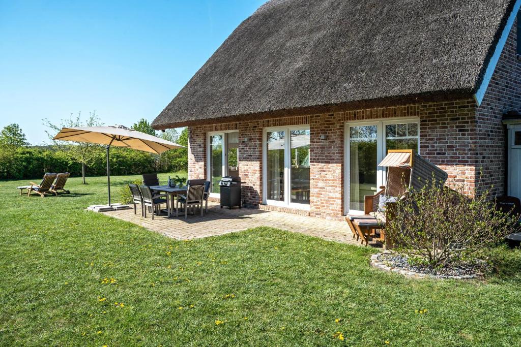 a brick house with a table and chairs and an umbrella at Reethaus Meerferien in Poseritz