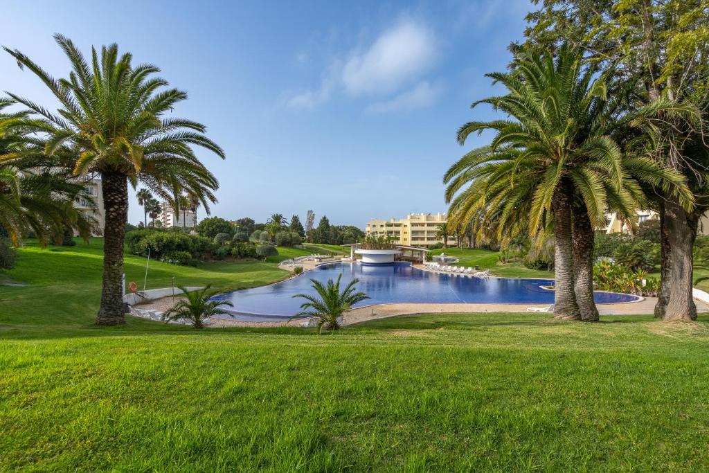 a pool with palm trees in a park at Villa Marachique 205 in Alvor