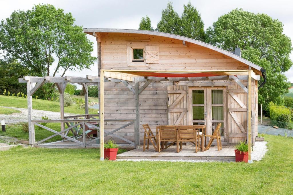 a wooden cabin with a table and chairs in the grass at Chalet 5 personnes, proche canal in Landeleau