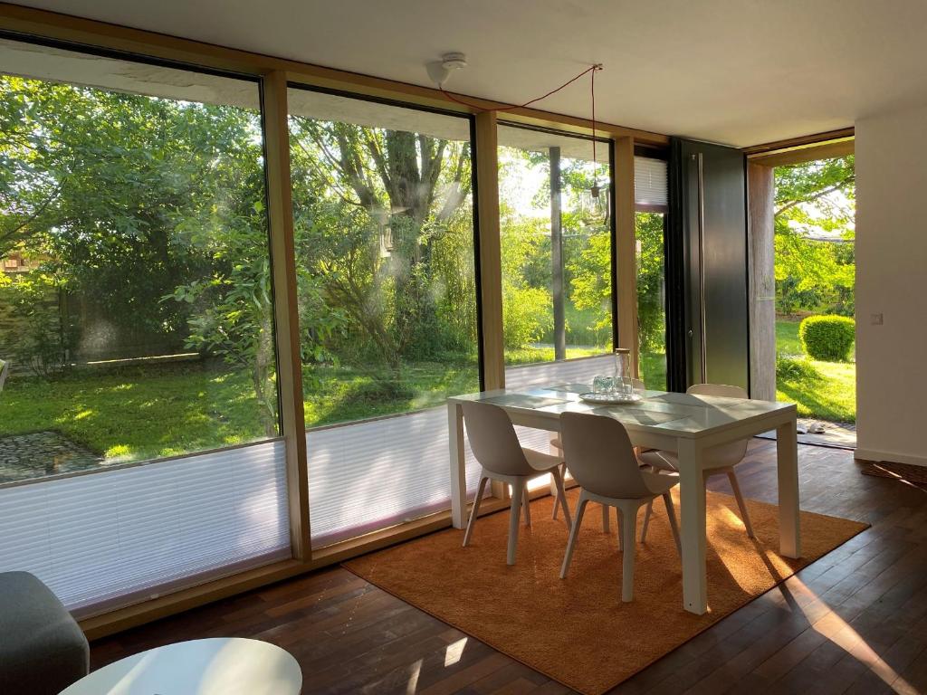 a dining room with a table and chairs and windows at Falterweg in Immenstaad am Bodensee