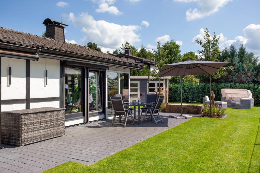 a patio with an umbrella and a table and chairs at Ferienhaus Sauerland am Hennesee in Meschede