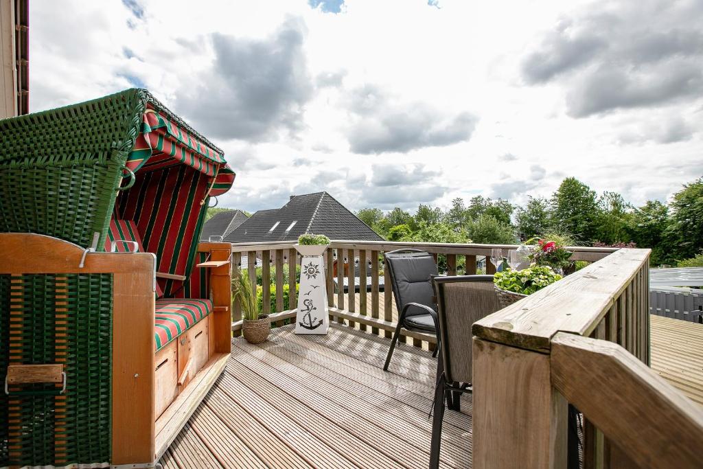 a wooden deck with chairs and a table on it at Ferienwohnung Huus 39 in Ostenfeld