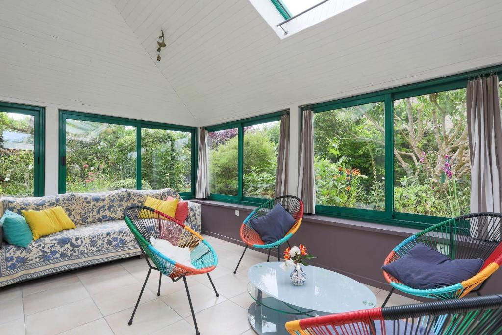a living room with a couch and chairs and windows at Gite les coquelicots Proche mer in Paimpol