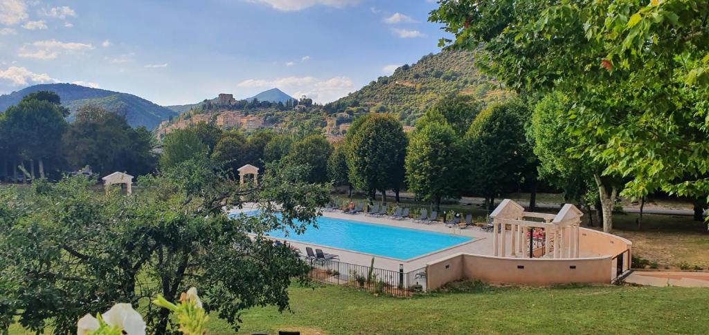 a swimming pool in a park with mountains in the background at Appartement Duplex Rez Jardin in Montbrun-les-Bains