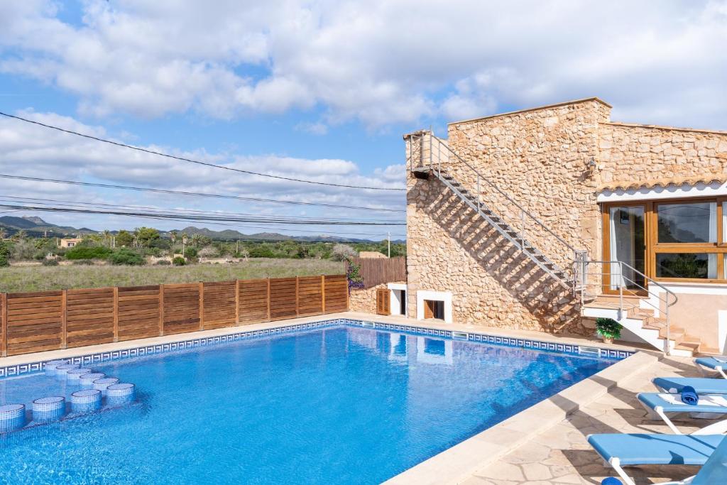 a swimming pool in front of a house with chairs at Finca Can Jeroni in Felanitx