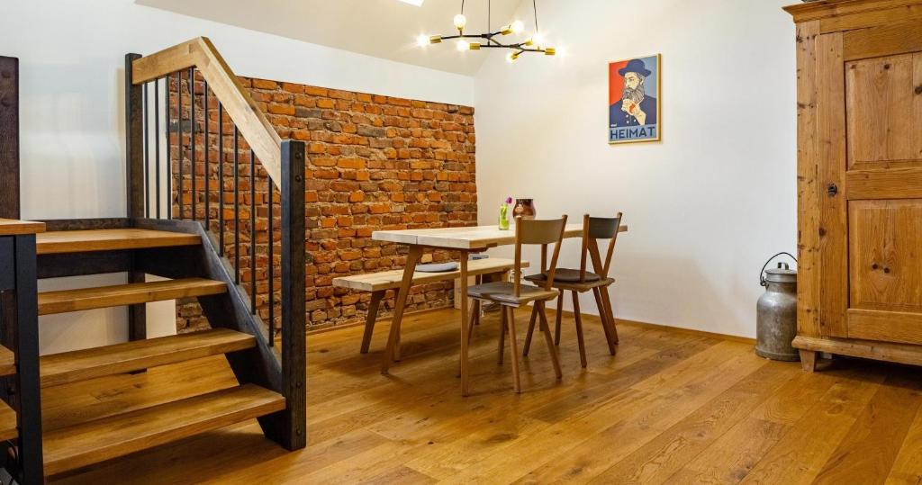 a dining room with a table and chairs and a brick wall at St Georgen Ferienwohnung 1 in Freiburg im Breisgau