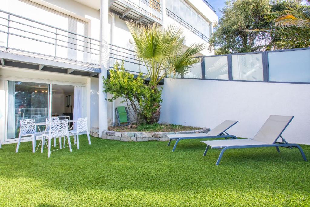 a patio with chairs and tables on the grass at Superbe F2 Spacieux - Saint Raphael in Saint-Raphaël