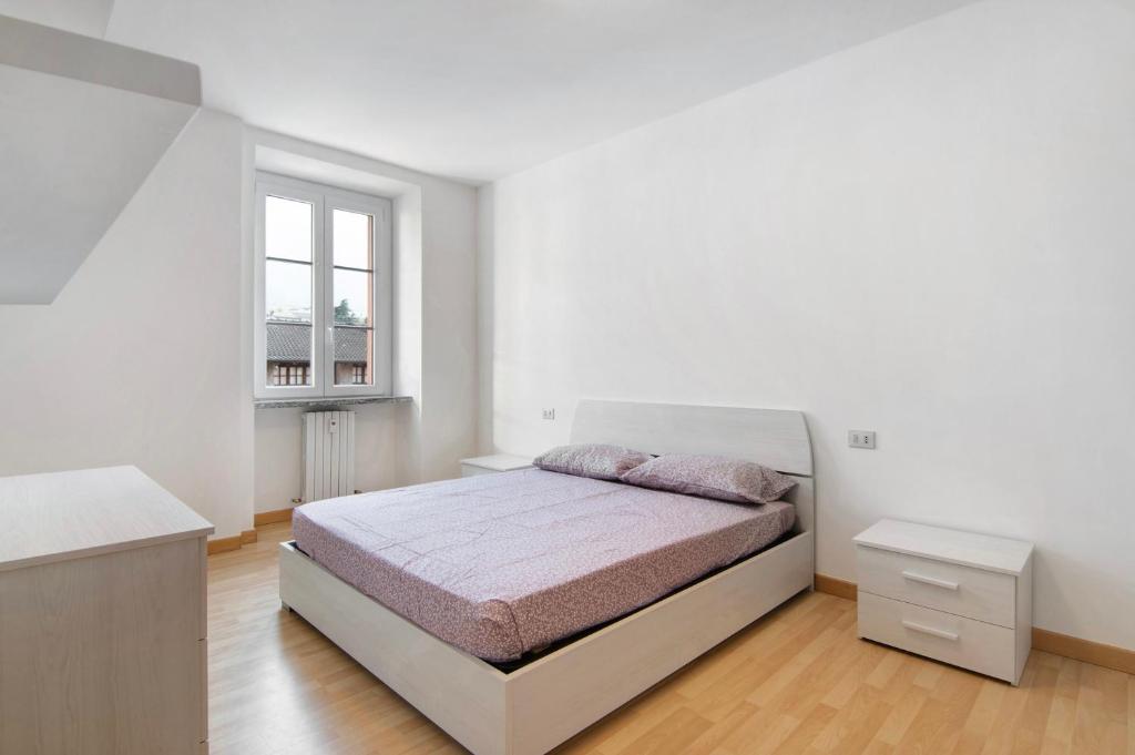 a white bedroom with a bed and a window at Greta House in Colico