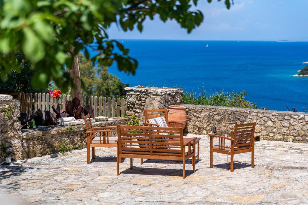 three wooden chairs and a table with a view of the ocean at Old manor house in Syvota