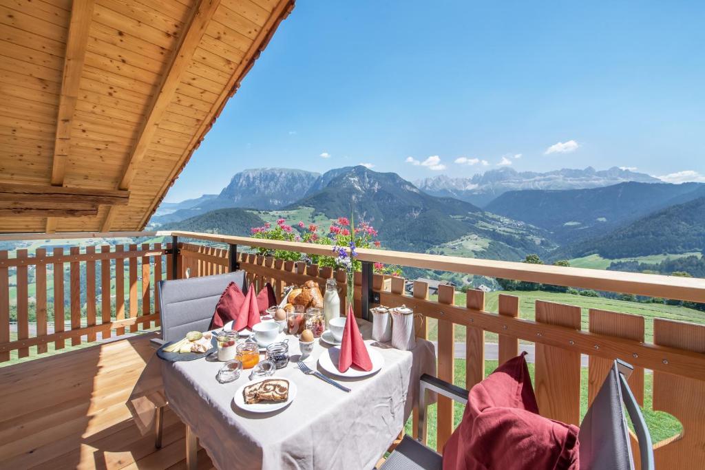 a table on a balcony with a view of mountains at Furnerhof Apt Stearnzauber in Collepietra