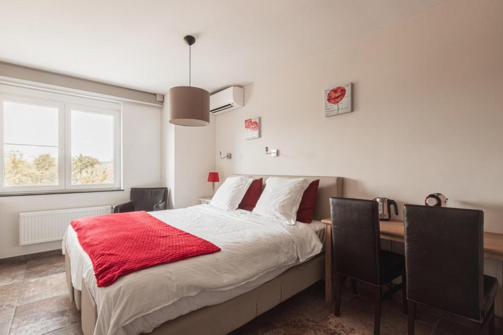 a bedroom with a bed and a desk with a red blanket at Guesthouse Amfora in Poperinge