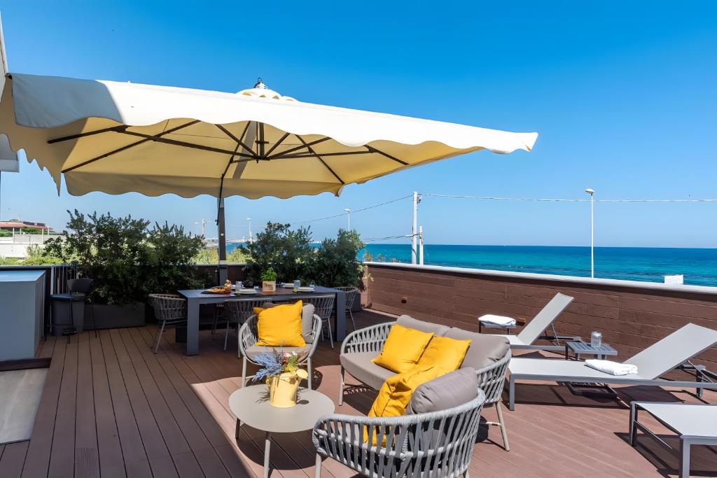 a patio with chairs and an umbrella and the ocean at Luxury terrazza in Bari