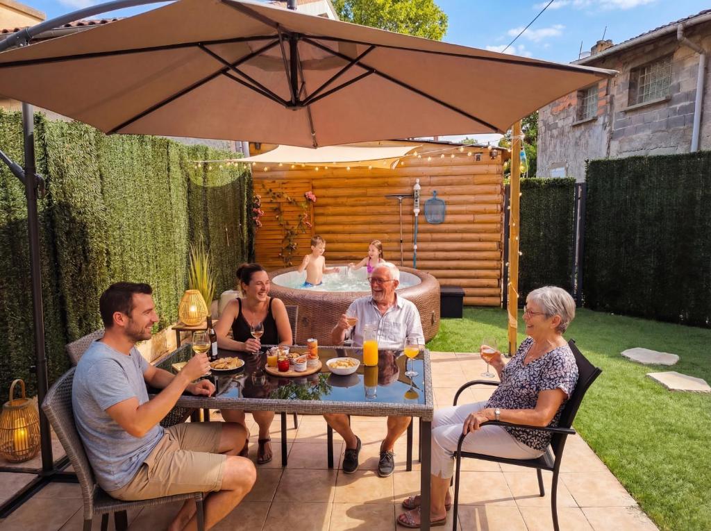 a group of people sitting around a table under an umbrella at Maison Althéa - Calme, Spa & Extérieur plein sud in Lempty