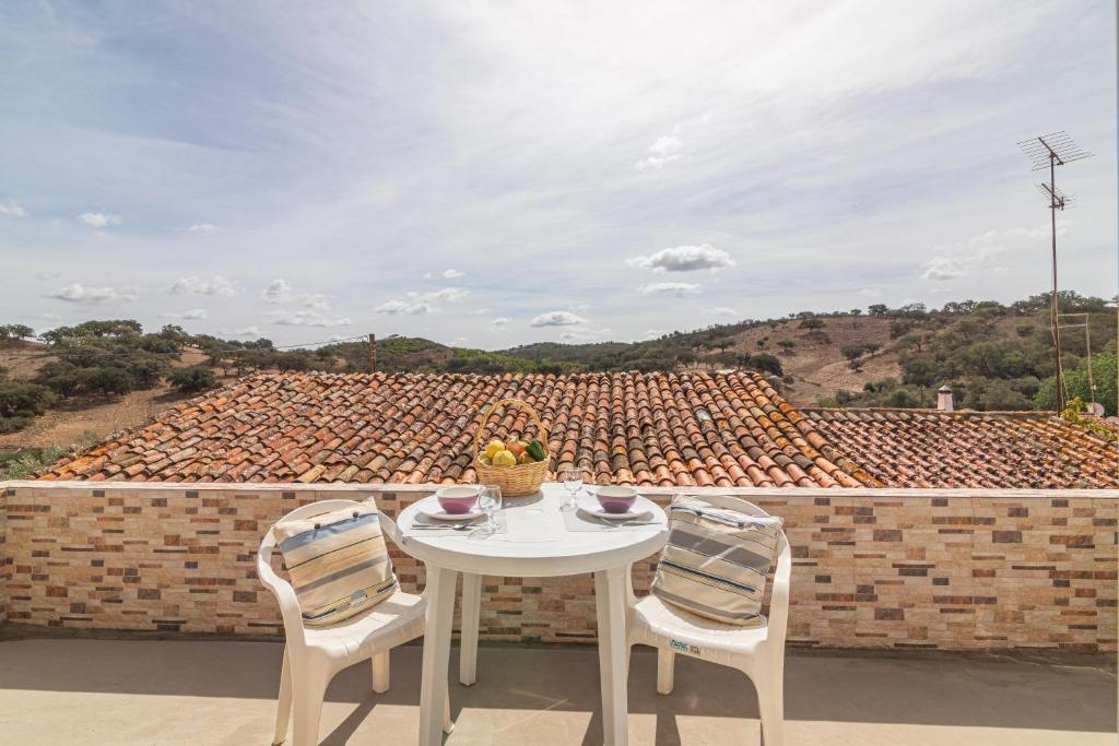 a white table and chairs on a patio with a roof at Casa das Bonecas in Farelos de Baixo