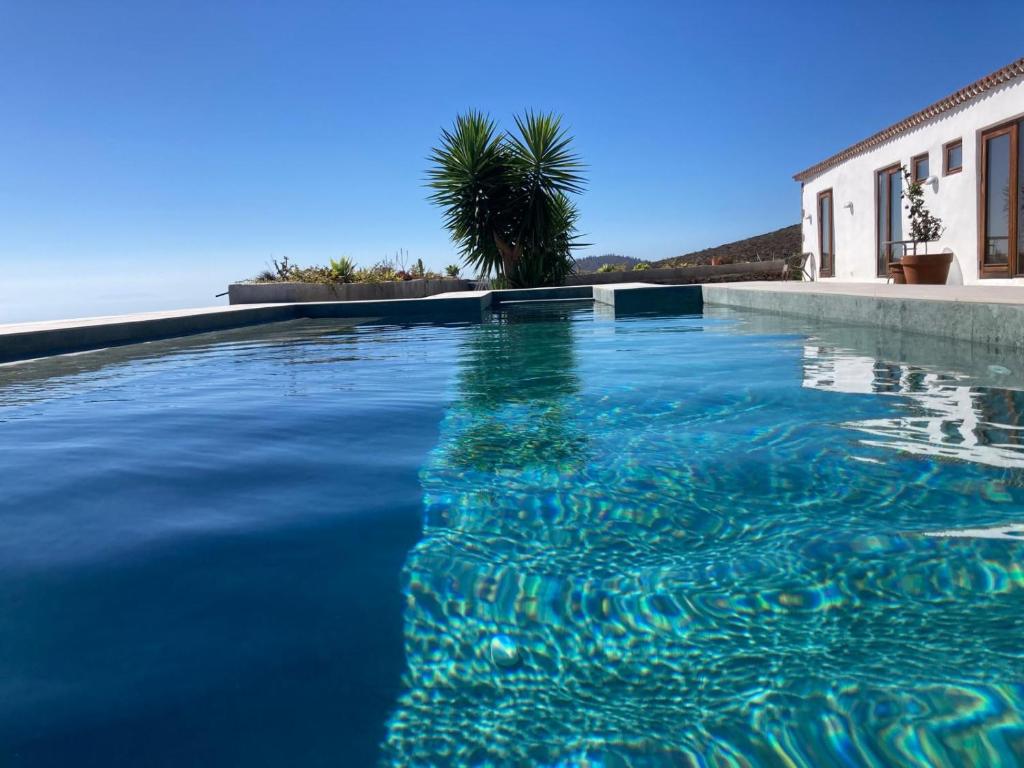 a swimming pool with blue water in front of a house at Casa del Cielo in Adeje