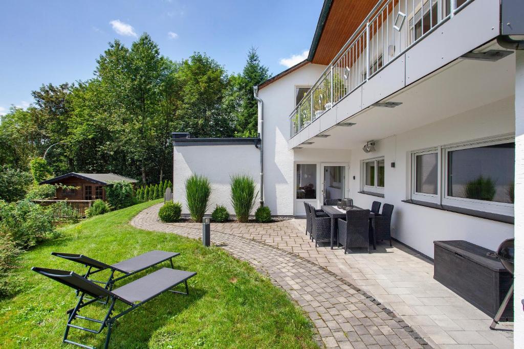a patio with a table and chairs in a yard at Ferienwohnung Am Wald in Eslohe
