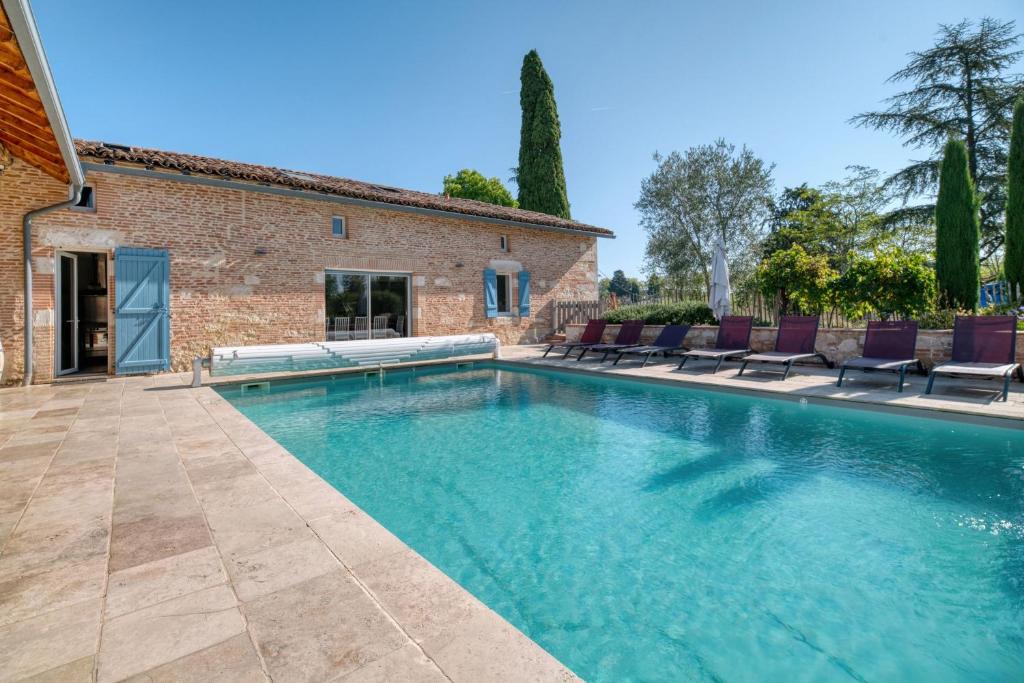 a swimming pool with chairs in front of a house at Villa Virginie gite 1 in Faudoas