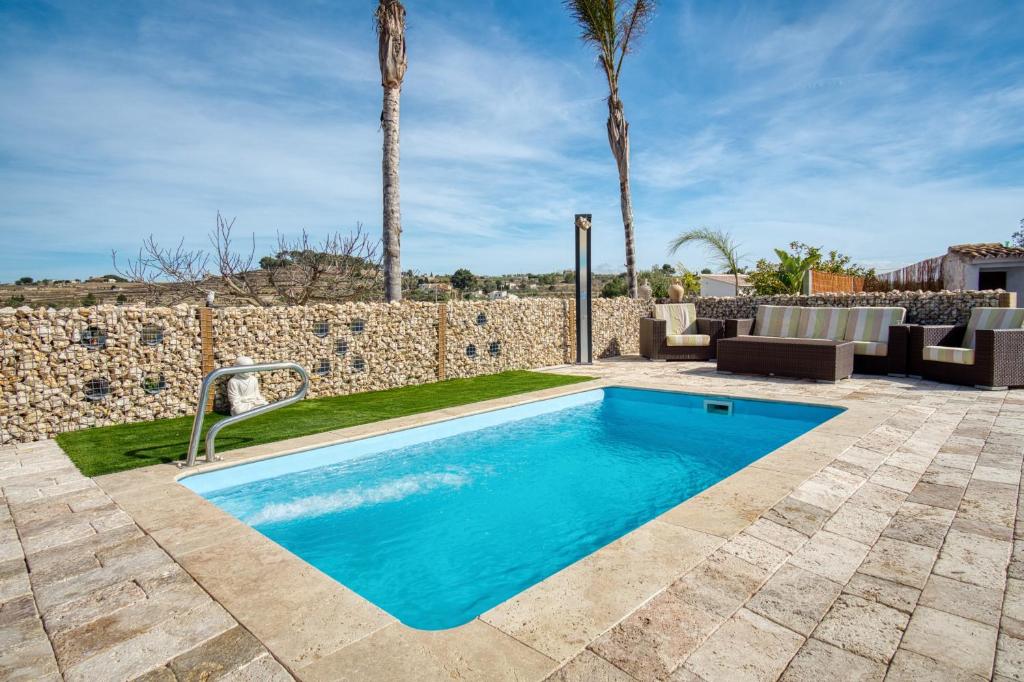 a swimming pool in a yard with a stone wall at Casa Stone in Benissa