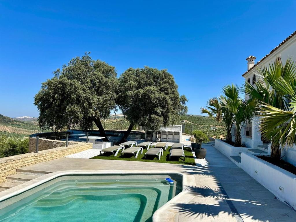 a swimming pool in a yard with chairs and a house at Avalon in Setenil in Setenil