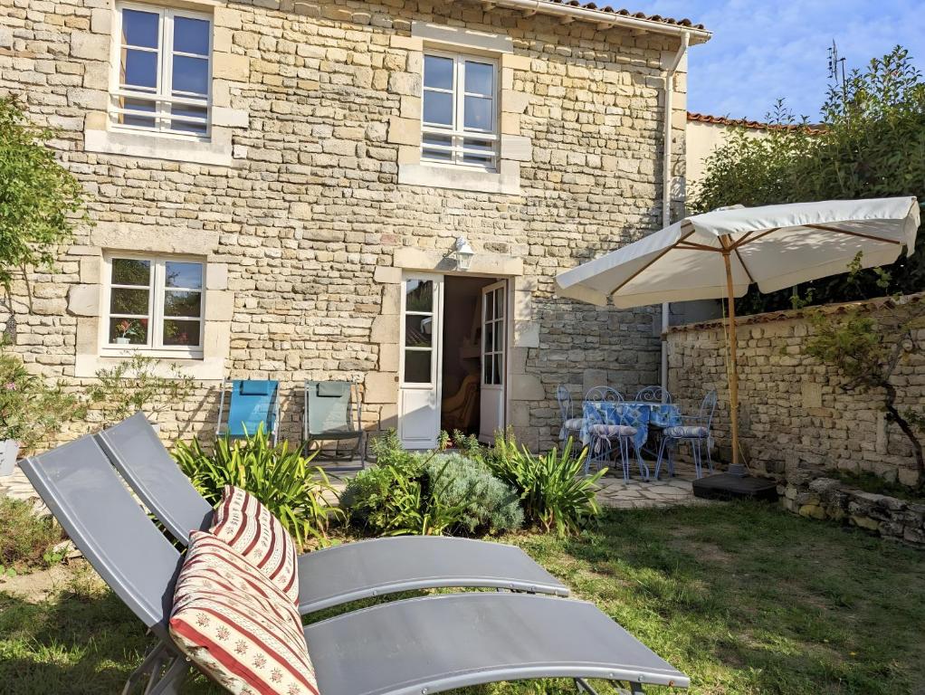 a stone house with a patio and an umbrella at Le Clos Pierreslogis in Theil-Rabier