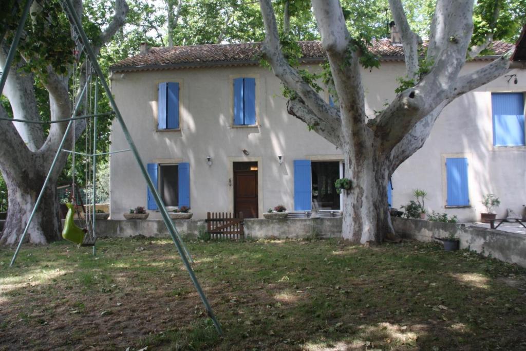 a white house with blue windows and a tree at Le Mas des Cigales in Avignon