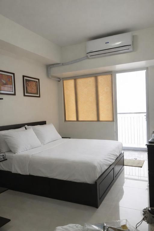 a bedroom with a large bed and a window at SMDC Tagaytay Condominium in Kaybagal
