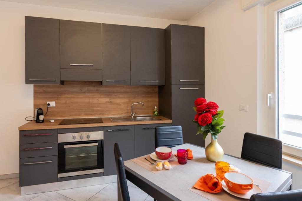a kitchen with a table with a vase of red roses at Casa Daniele Vista Mare - Sanremo in Sanremo