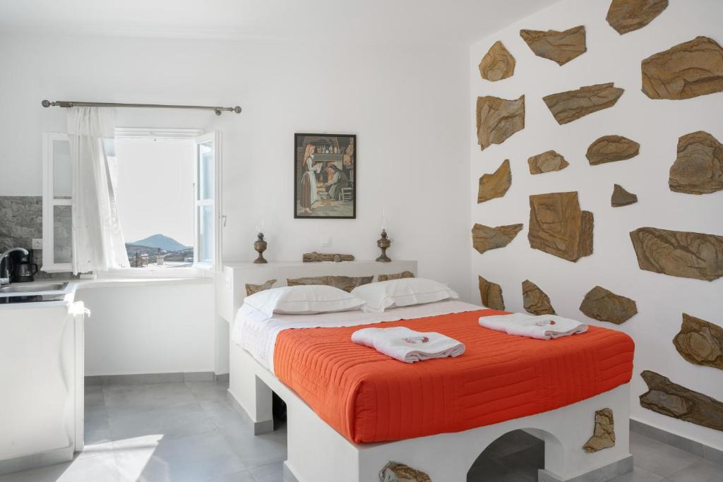 a bedroom with a bed with an orange blanket at Politimis Studio N4 in Amorgos