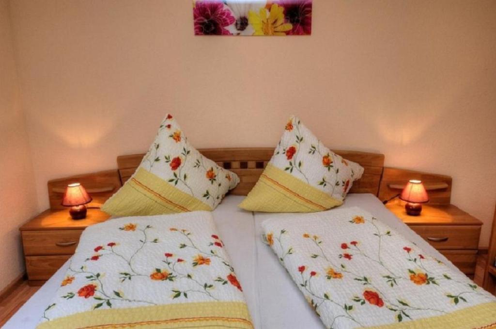 a bedroom with two beds with pillows and two lamps at Dischhansenhof in Glottertal