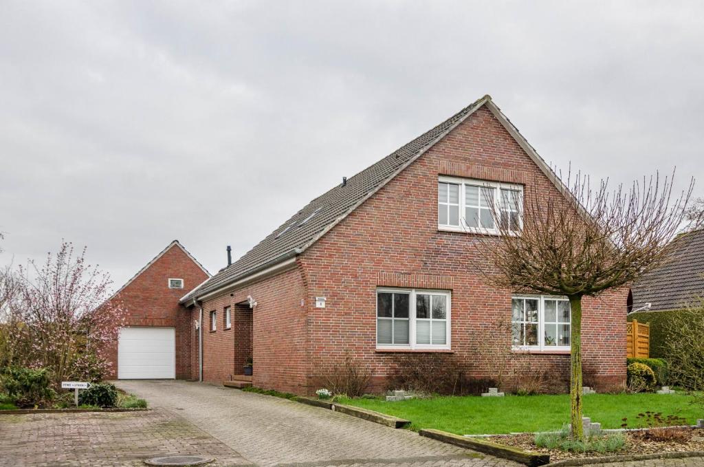 a red brick house with a white garage at Ferienwohnung Utkiek in Ihlow