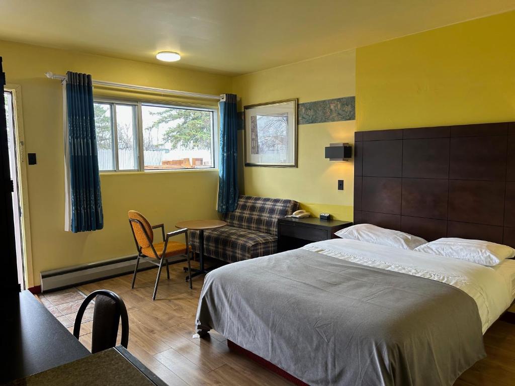 a bedroom with a bed and a table and a chair at Motel R-100 in Longueuil