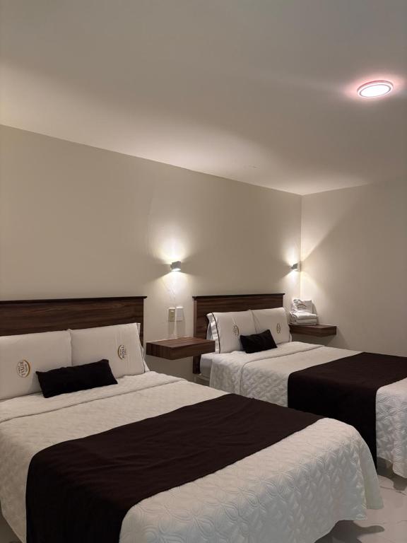 ein Hotelzimmer mit zwei Betten mit schwarz-weißer Bettwäsche in der Unterkunft Hotel Royal Puebla in Puebla