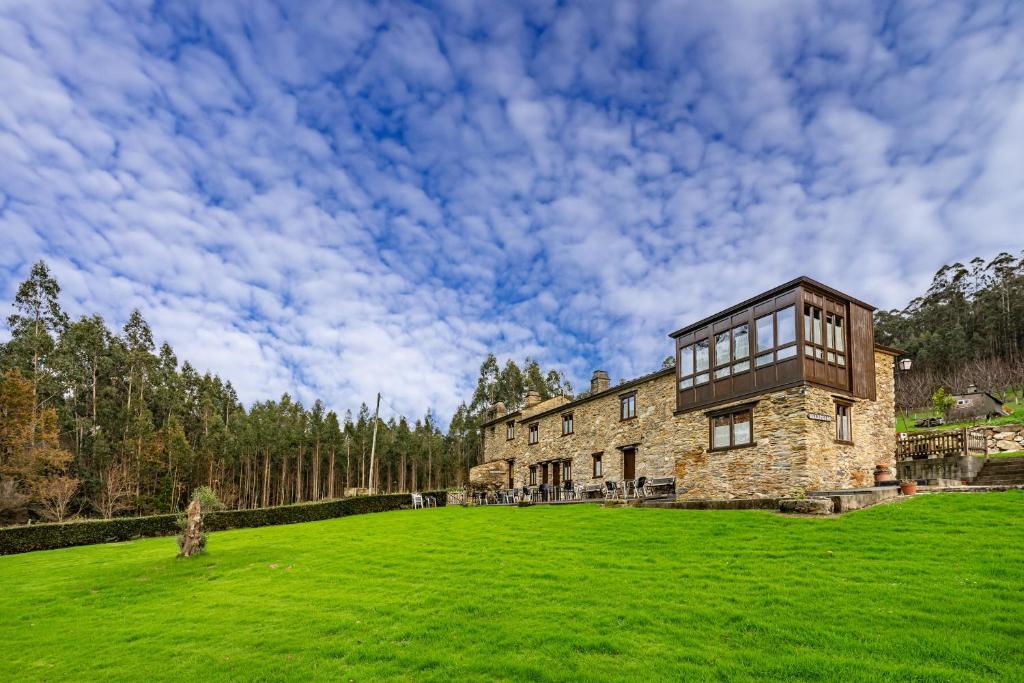 a large stone house on a grassy field at Eiron in O Porto de Espasante