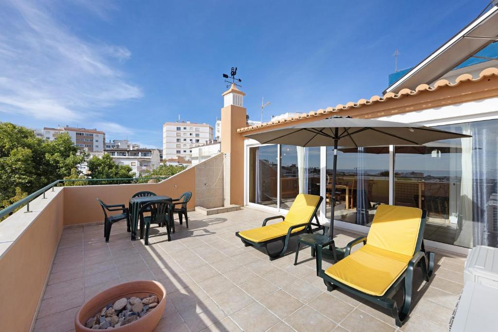 a patio with yellow chairs and a table and an umbrella at My Friendly House in Lagos