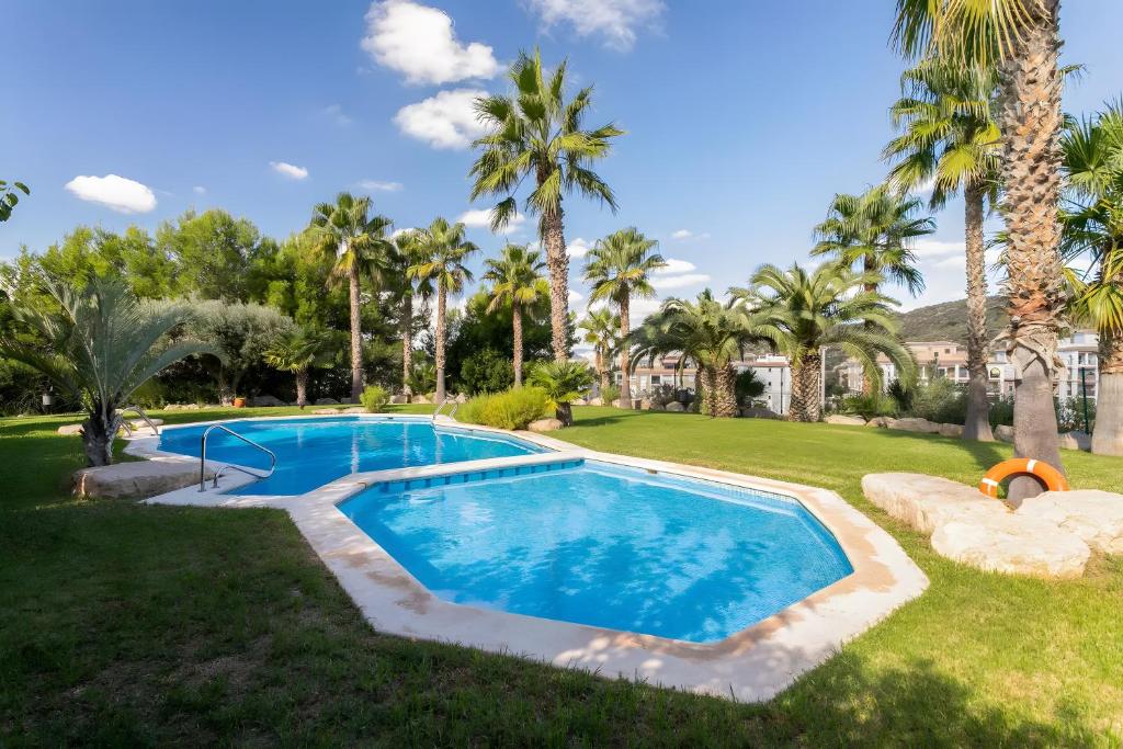 a swimming pool in a yard with palm trees at Appartement avec 2 piscines in Mutxamel