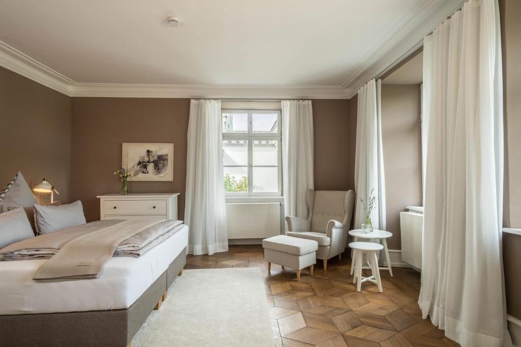 a bedroom with a bed and a chair and a window at Schloss Kirchberg - Rose in Immenstaad am Bodensee
