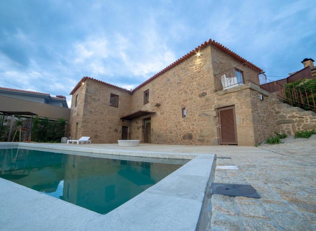 a house with a swimming pool in front of a building at Villae Carreiro in Palmeira