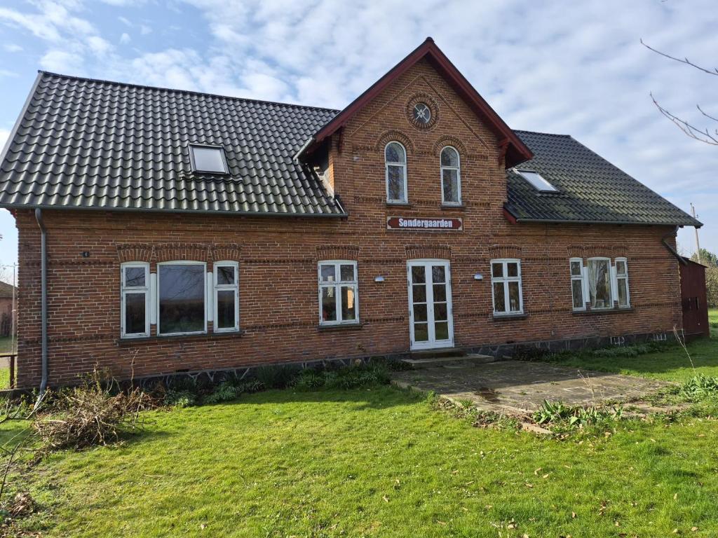 a brick house with a large yard in front of it at Søndergaarden in Øster Ulslev