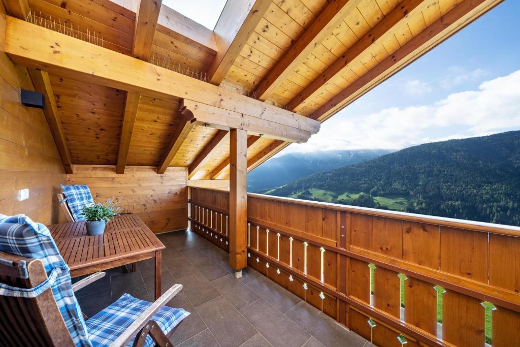 a log cabin balcony with a table and chairs at Matscherhof Ferienwohnung Helena in Santa Valpurga