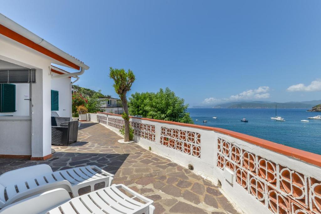 a balcony with white chairs and a view of the water at Villa Oda - Bilocale sul mare in Capoliveri