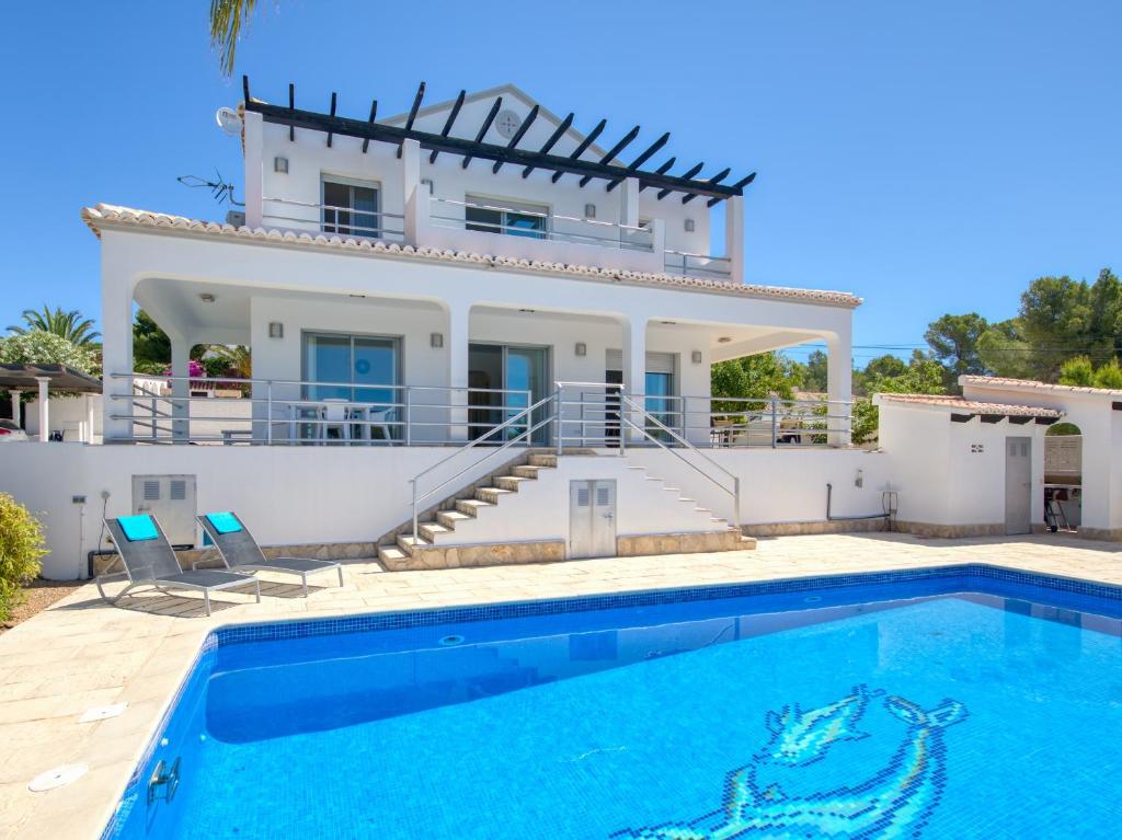 a villa with a swimming pool in front of a house at Fustera in Benissa