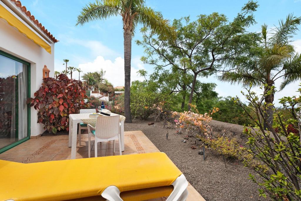 a patio with a table and chairs and palm trees at La Villa La Palma- 1 dormitorio A in Los Barros