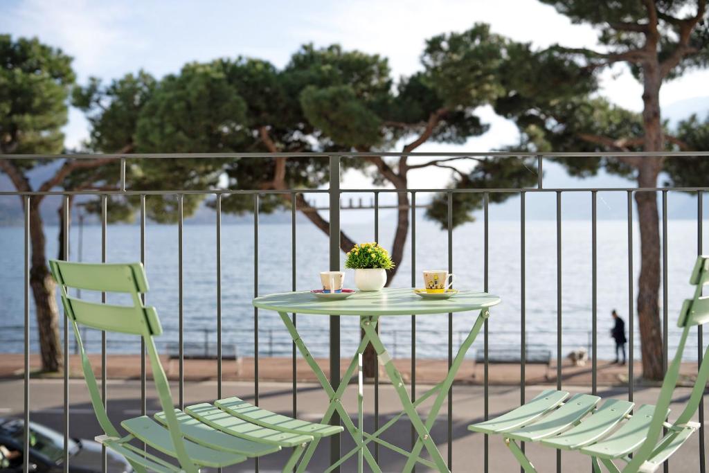 a table with two chairs and a table with cups and a plant at Domaso front lake in Domaso