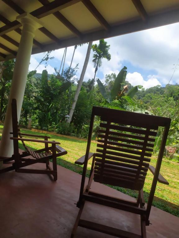 two chairs sitting on a porch with a view of a field at Thotupala Eco Lodge in Nilweligama
