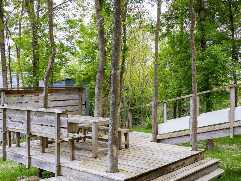 a wooden deck in the woods with trees at La Cafoutche de Minus rénovée 2pers in Gommenecʼh
