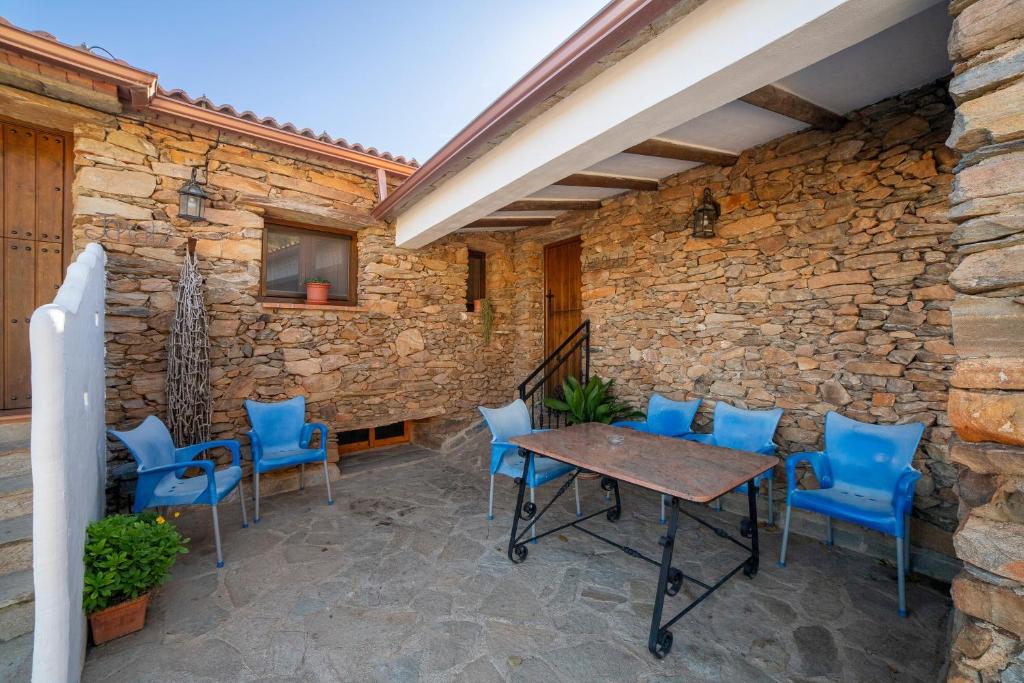 a patio with blue chairs and a table and a stone wall at Casa Rural Albaida in Laroya